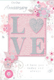 This anniversary card unfolds like a soft, romantic scene, echoing the tenderness of sharing fresh flowers at home in Oxted. Dominating the design is the word LOVE, crafted in raised, glitter-edged letters that appear almost velvety to the touch. The glitter is applied with precision, giving a gentle, pearlescent gleam whenever the card tilts in the light, much like sunlight glancing across petals in a florist's window near the station. The letterforms sit against a blush-pink central panel, which is surrounded by an airy border of illustrated blossoms and spiralling vines. These flowers are stylised yet intricate, with petals shaded in soft blush, muted mauve, and creamy white, all outlined in the finest lines of grey and silver. Some details glint with hints of silver foil, suggesting dewdrops or tiny pieces of jewellery woven into an anniversary bouquet. The foliage curls gracefully around the blooms, filling the space without crowding it, and small flourishes, like swirling lines and subtle butterfly shapes, add a sense of movement and quiet joy. The background remains a pale, comforting pink, unifying the design and reinforcing its romantic tone. The scripted phrases On Our Anniversary and I love you today and always are written in an understated, flowing typeface that feels personal, as if carefully chosen for a cherished partner. Overall, the card resembles a hand-arranged paper bouquet, combining texture, soft colour, and thoughtful detail, the sort of keepsake someone in Oxted might tuck away with love letters and memories of flowers shared over many years.
